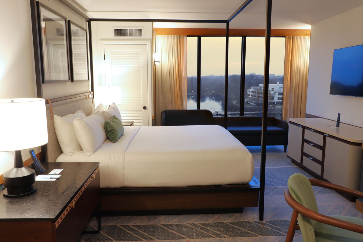 The Presidential Suite Bedroom at Merriweather Lakehouse Hotel with a canopy bed, widescreen tv, and lake view.