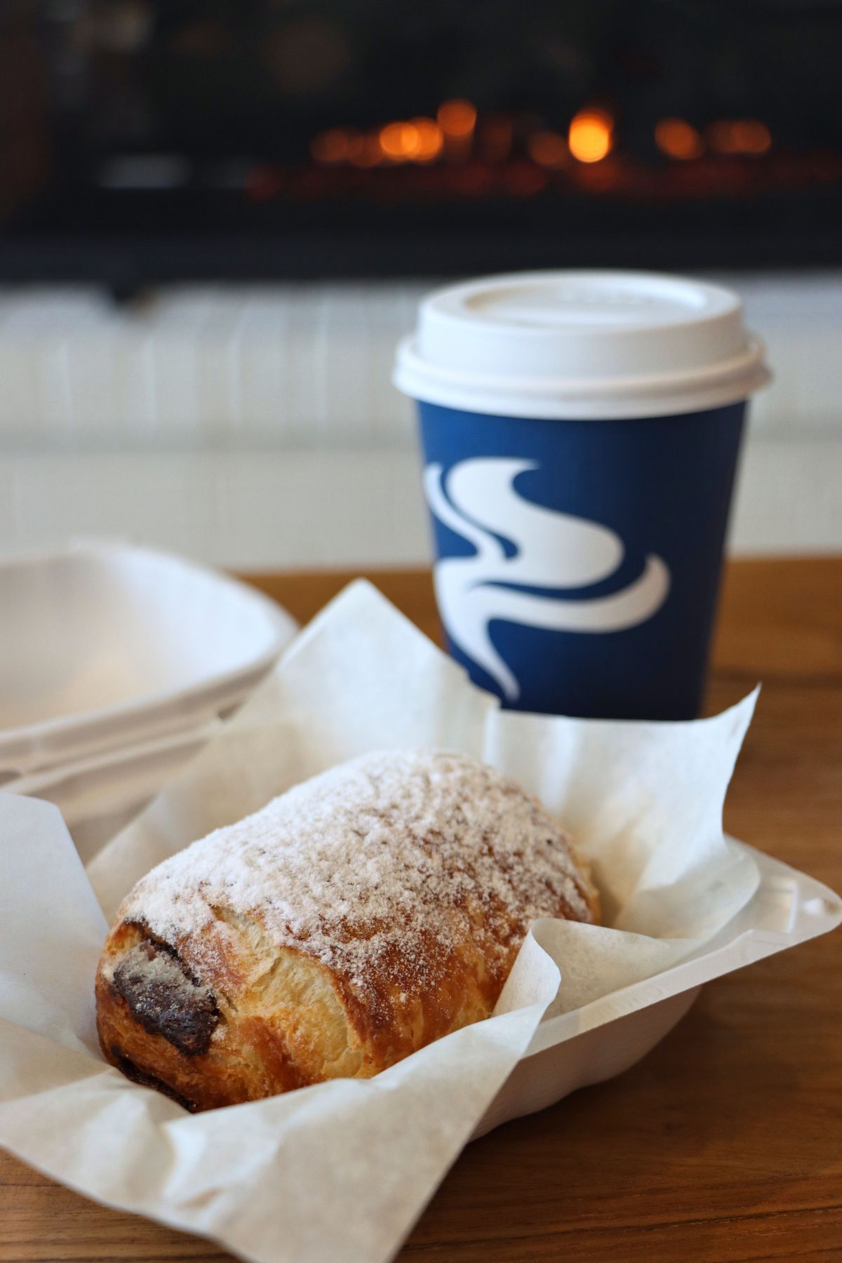 A fresh chocolate croissant and Lavazza coffee in front of the fireplace at Osprey Cafe 